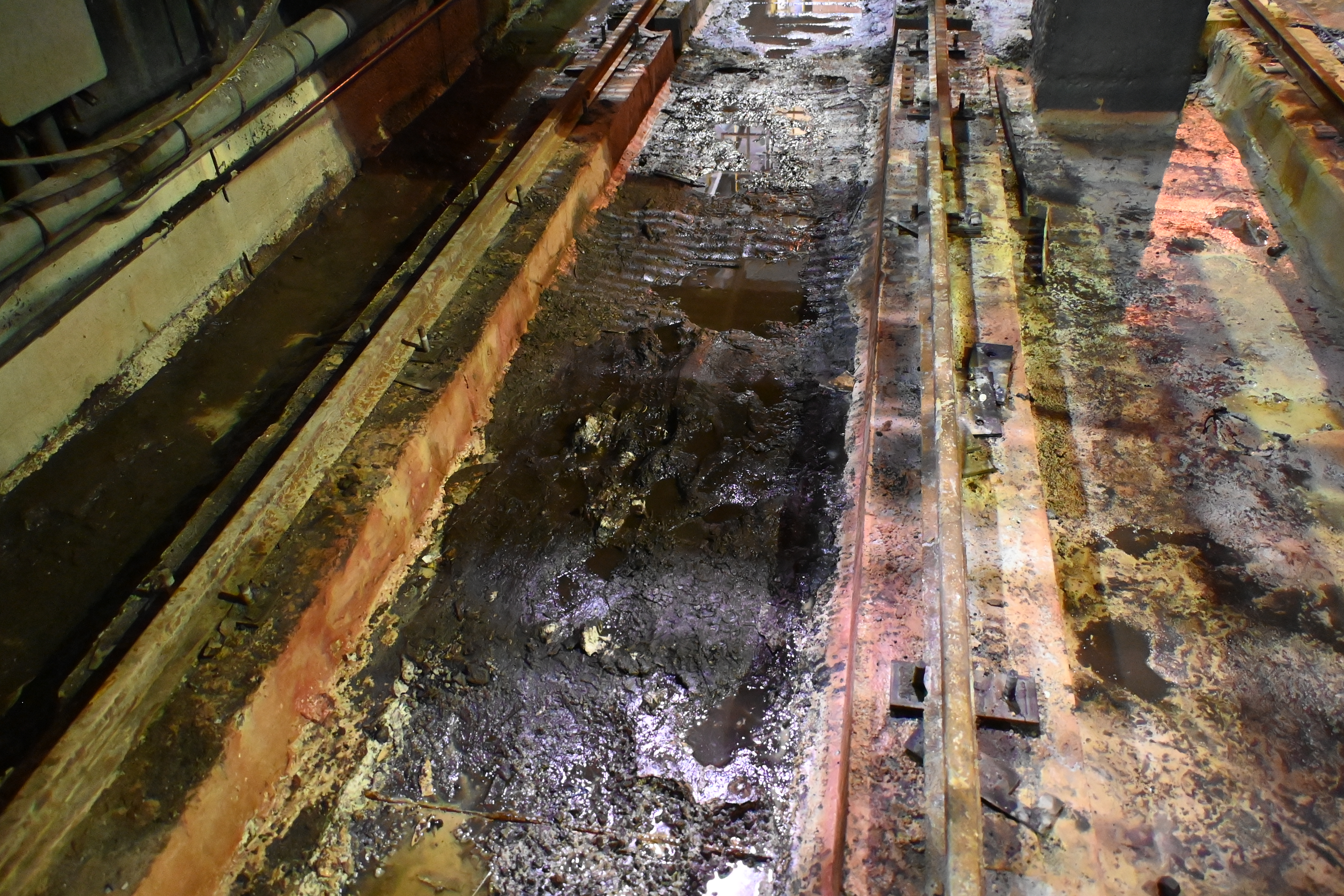 Acid-rich sludge coating the car well floor before restoration